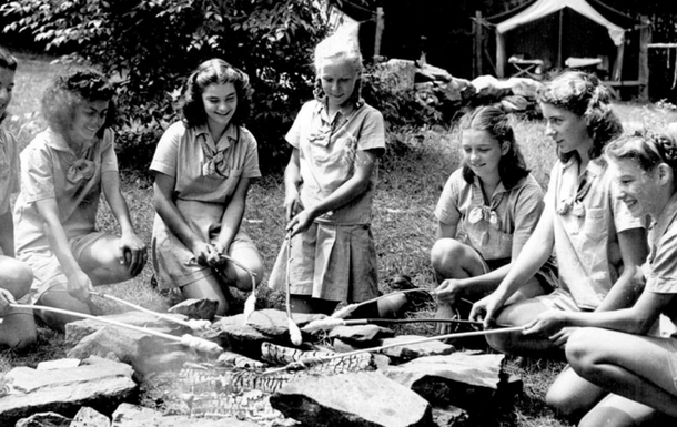 Girl Scouts toasting marshmallows at a campfire in 1963