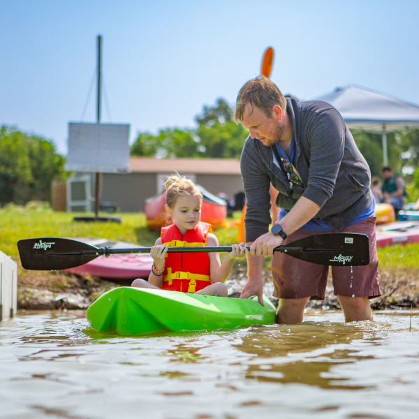 Girl Scout camp counselor at Camp Gamble helps young girl learn to kayak